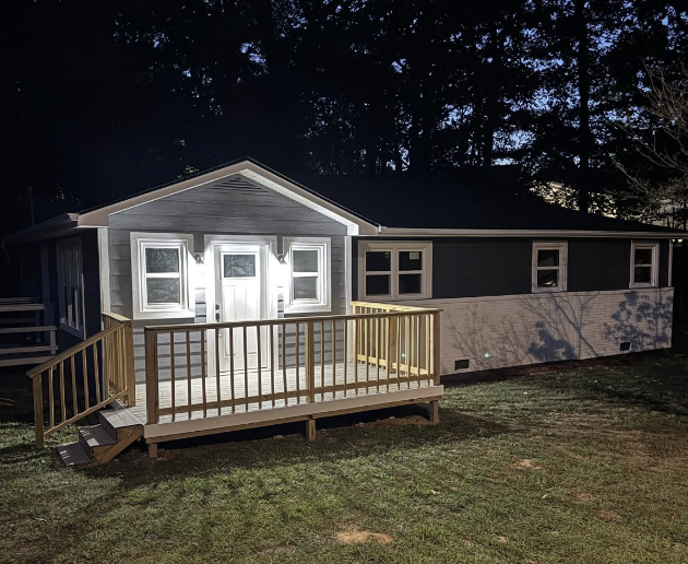 Same Tennessee house after work: new front deck, fresh grey siding and painted white brick